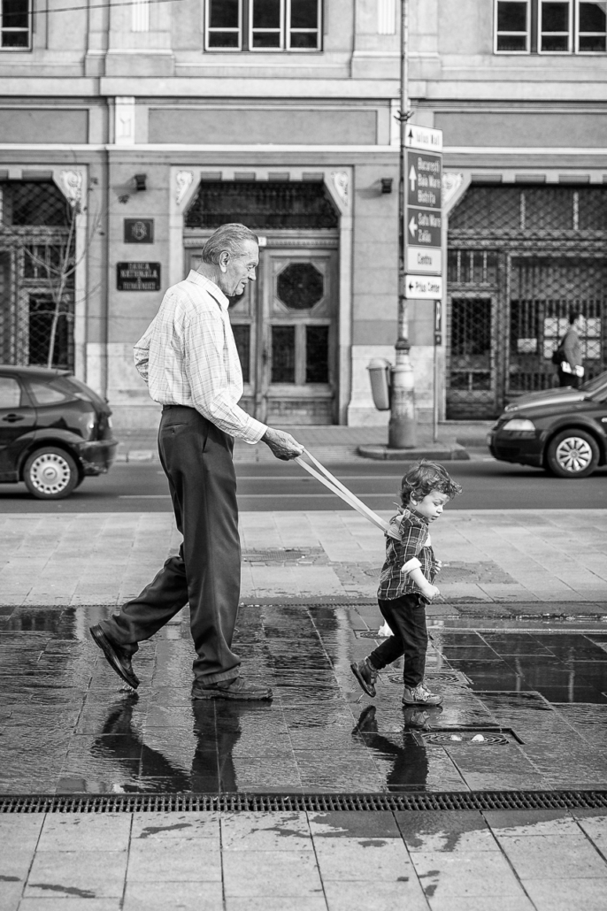 On a tight leash. A kid and his grandfather, playing between the water fountains in Cluj-Napoca, Romania.